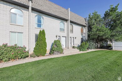 View of side of home featuring a shingled roof, mansard roof, a yard, and brick siding