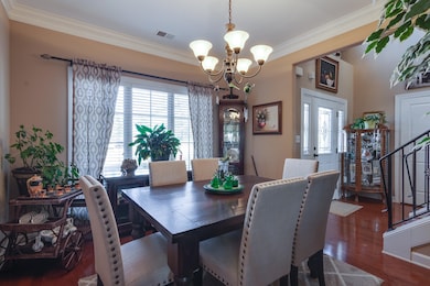 Dining area featuring crown molding, dark wood-style floors, and a chandelier