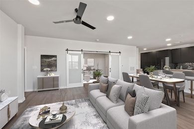 Living room with a barn door, ceiling fan, recess