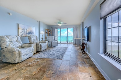 Living room with a ceiling fan and stone tile flooring