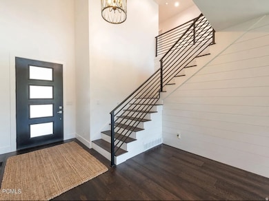 Foyer entrance featuring stairway, dark wood finished floors, and a high ceiling