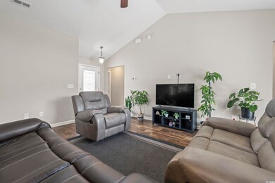 Living room with dark wood finished floors, vaulted ceiling, baseboards, and ceiling fan
