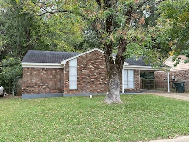 View of front of home with a front lawn, an attached carport, and brick siding