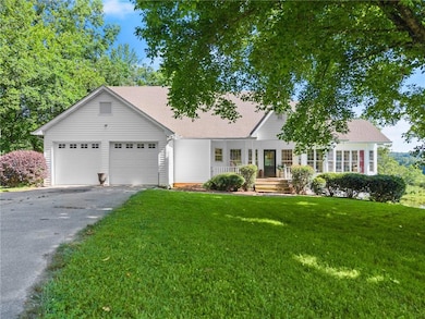 View of front of house with asphalt driveway, an attached garage, and a front yard