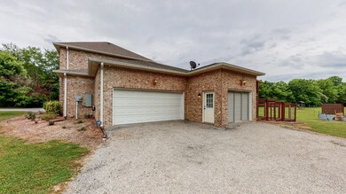 Side-load 3 car garage with one door screened. Garage is accessed from the second gravel driveway.