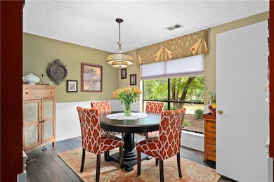 Dining space featuring hardwood / wood-style flooring, a textured ceiling, and wainscoting
