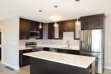 Kitchen with stainless steel appliances, a sink, dark brown cabinetry, and light countertops