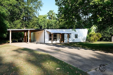 View of front of home with a front yard, concrete driveway, and a carport