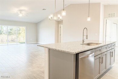 Kitchen featuring gray cabinets, a center island with sink, dishwasher, hanging light fixtures, and light stone counters