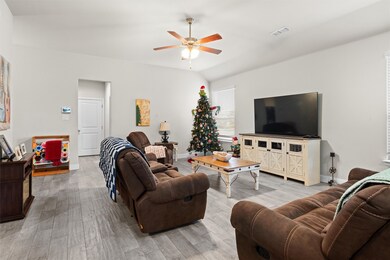 Living room featuring light wood-style floors, a ceiling fan, and lofted ceiling