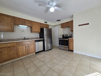 Kitchen with decorative backsplash, brown cabinets, light countertops, and appliances with stainless steel finishes