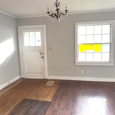 Unfurnished dining area with ornamental molding, a chandelier, and dark wood-style flooring