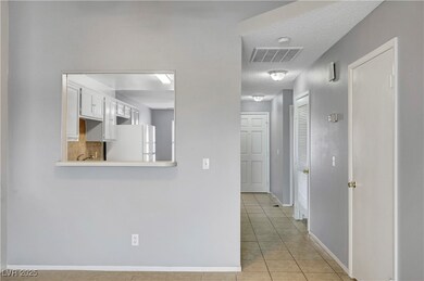 Corridor featuring light tile patterned floors and a textured ceiling