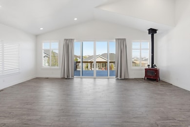 Empty room featuring healthy amount of natural light, a wood stove, wood finished floors, recessed lighting, and high vaulted ceiling