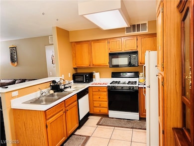 Kitchen with white appliances, a peninsula, light