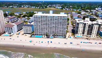 Drone / aerial view of a pool, apartment complex / building, and a large body of water