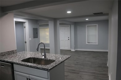 Kitchen with dark wood finished floors, visible vents, a sink, dark stone countertops, and dishwashing machine