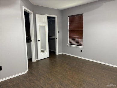 Unfurnished bedroom featuring baseboards, dark wood-style floors, and a closet