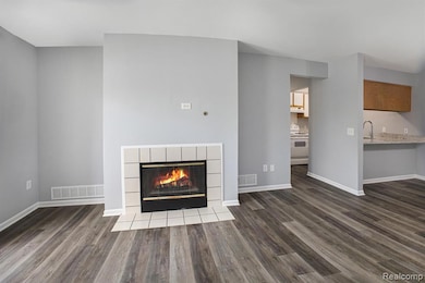 Unfurnished living room featuring dark wood finished floors and a tile fireplace