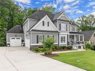 View of front of home featuring board and batten siding, an attached garage, covered porch, a front lawn, and driveway