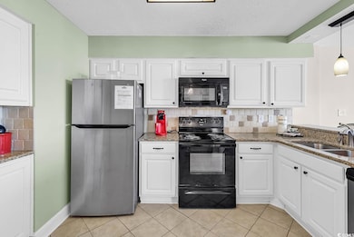 Kitchen featuring tasteful backsplash, black appliances, light stone countertops, white cabinets, and a textured ceiling