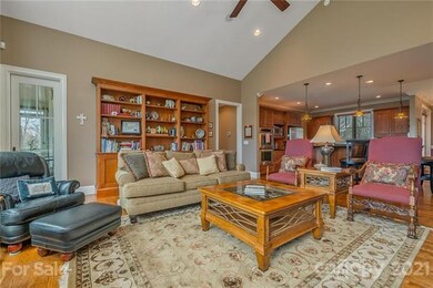 Sitting/Livingroom area with high ceilings, large windows, built in bookshelf and a fireplace - opens to the kitchen