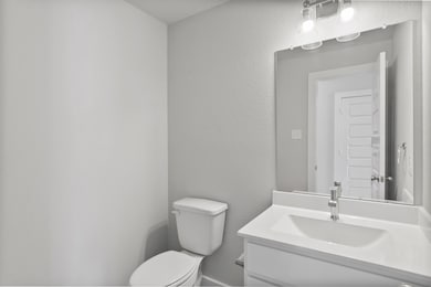 The half bathroom, conveniently situated on the 1st floor, is adorned with contemporary finishes. Light cabinets paired with a light countertop, custom wall paint, and sleek faucet combine to create a bright and inviting space. Sample photo of completed home. As-built color and selections may vary.