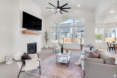 Living room with abundant natural light, a large fireplace, high vaulted ceiling, recessed lighting, and a ceiling fan