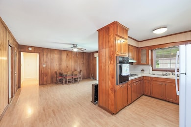 Kitchen featuring oven, light countertops, stainless steel gas cooktop, a sink, and light wood-style floors