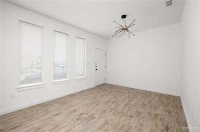 Spare room with a chandelier, light wood-type flooring, and baseboards