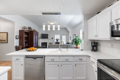 Kitchen with sink, white cabinets, hanging light f