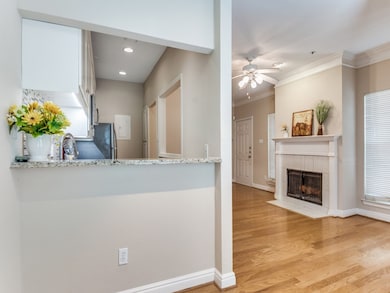 Kitchen featuring a ceiling fan, light wood finished floors, ornamental molding, white cabinetry, and a fireplace