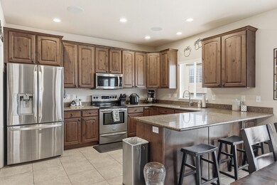 Kitchen with stainless steel appliances, dark stone countertops, a kitchen bar, light tile patterned flooring, and a peninsula