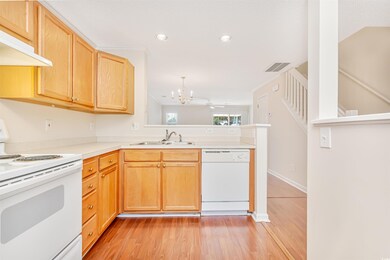Kitchen with exhaust hood, ceiling fan with notable chandelier, light hardwood / wood-style floors, and white appliances