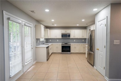 Kitchen with light tile patterned floors, stainless steel appliances, backsplash, a textured ceiling, and recessed lighting