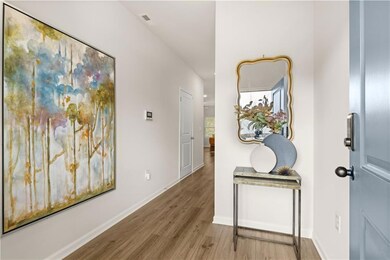 Hall with wood finished floors, visible vents, and