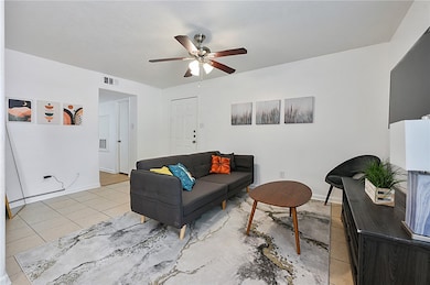Spacious living room featuring light tile patterned floors and a ceiling fan