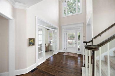 Foyer entrance featuring wood finished floors, plenty of natural light, stairway, french doors, and a high ceiling