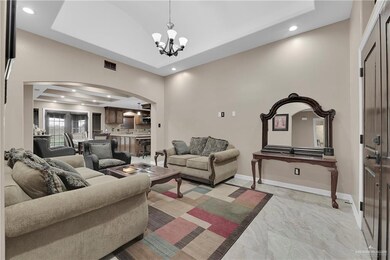 Tiled living room with a notable chandelier, a raised ceiling, and a high ceiling