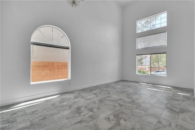 Spare room with a high ceiling, plenty of natural light, and marble finish flooring