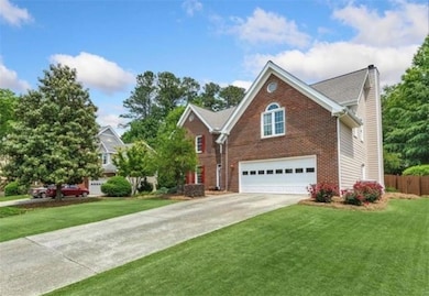 View of front of property with a chimney, driveway, brick siding, and an attached garage