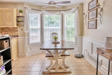 Dining space with healthy amount of natural light, light tile patterned floors, a textured ceiling, a wainscoted wall, and a decorative wall