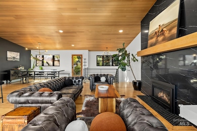 Living area featuring a fireplace, wood ceiling, wood finished floors, recessed lighting, and a chandelier
