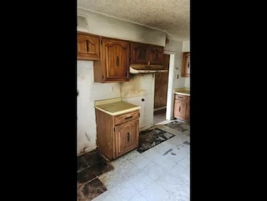 Kitchen with a textured ceiling, light countertops, and brown cabinetry