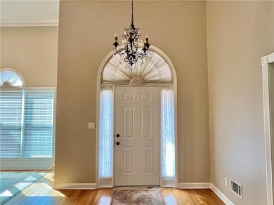 Foyer entrance with wood finished floors, healthy amount of natural light, and a chandelier