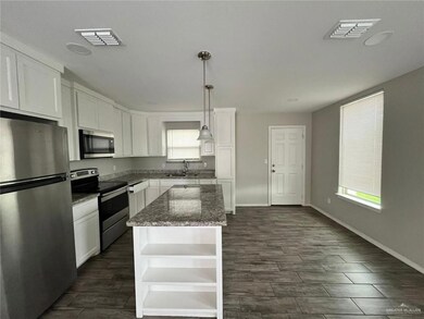 Kitchen featuring appliances with stainless steel finishes, open shelves, white cabinets, and dark stone counters
