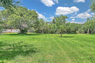 View of grassy yard with a view of trees