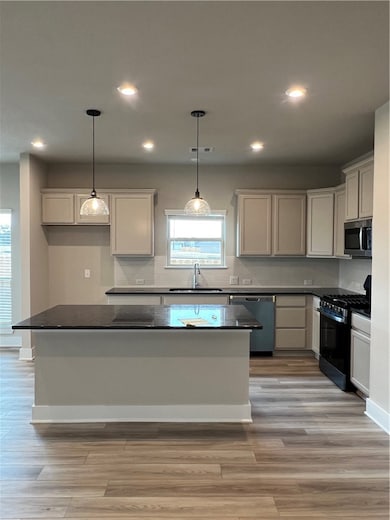 Kitchen featuring stove, dishwasher, a sink, dark