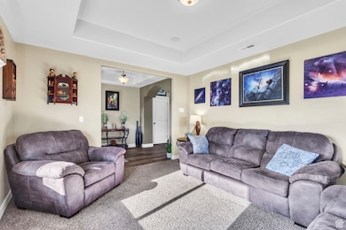 Carpeted living area featuring a tray ceiling and arched walkways