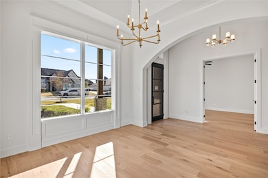 Unfurnished dining area with a chandelier, light wood-style flooring, and arched walkways